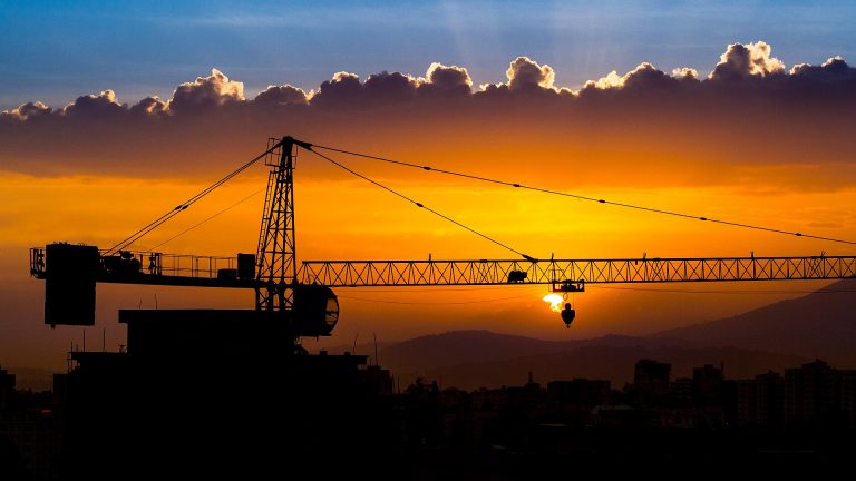 Silhouette of a construction crane against an orange sunset over the Addis Ababa skyline
