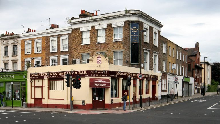 Corner storefront of Marathon Restaurant and Bar, an Ethiopian restaurant on Caledonian Road in Islington, London, with its red and cream sign