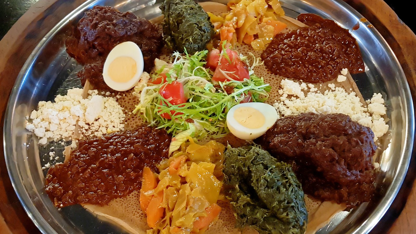 A platter of Ethiopian wat stews and boiled eggs served on injera